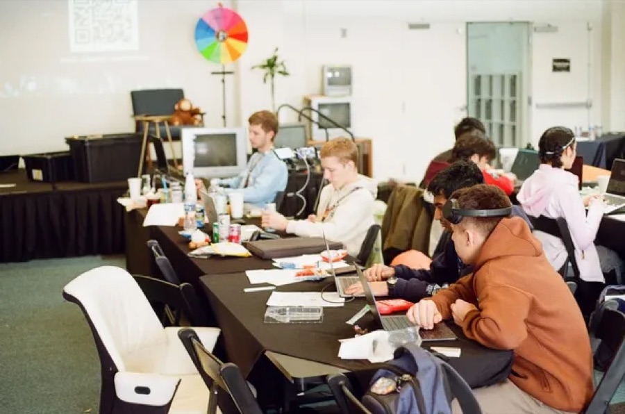 Hack Clubbers at laptops around a long table