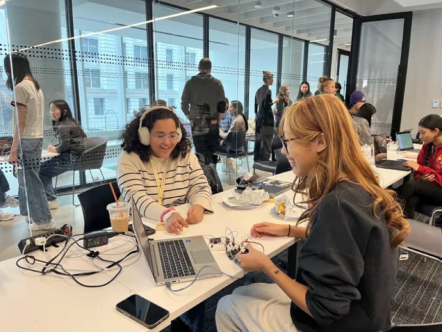 Two Hack Clubbers wiring a circuit next to a laptop